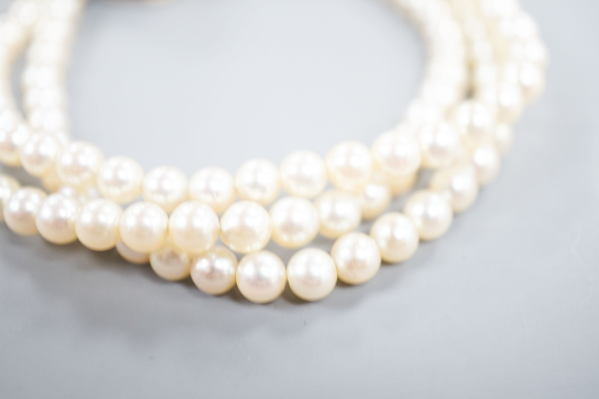 An early 20th century triple strand cultured? pearl bracelet, with rose cut diamond and cabochon amethyst set yellow metal clasp, 17.5cm, gross weight 21 grams.